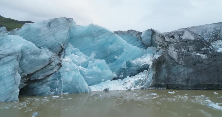 Chunks of snow and ice sit in the sea below a rock wall