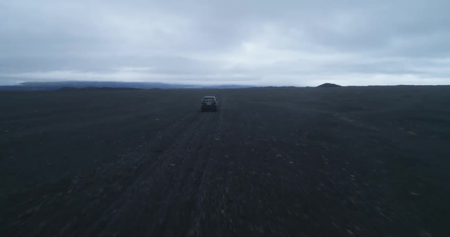 A vehicle speeds through a vast dirt field