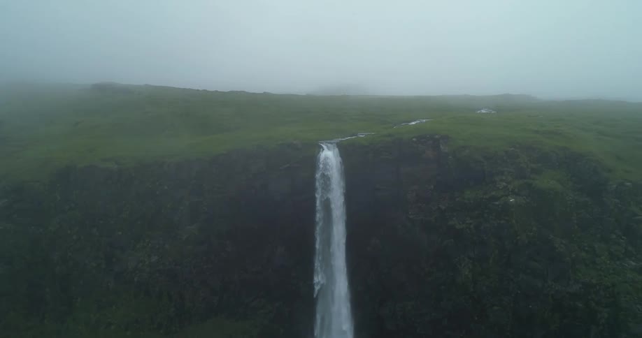 Birds fly around the waterfall on a very foggy day