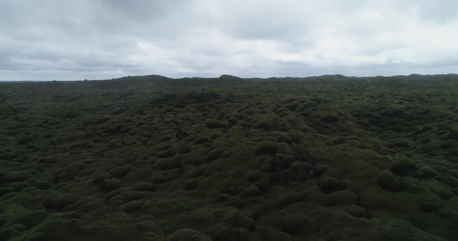 A landscape with hills and dirt with the sky and clouds in the background
