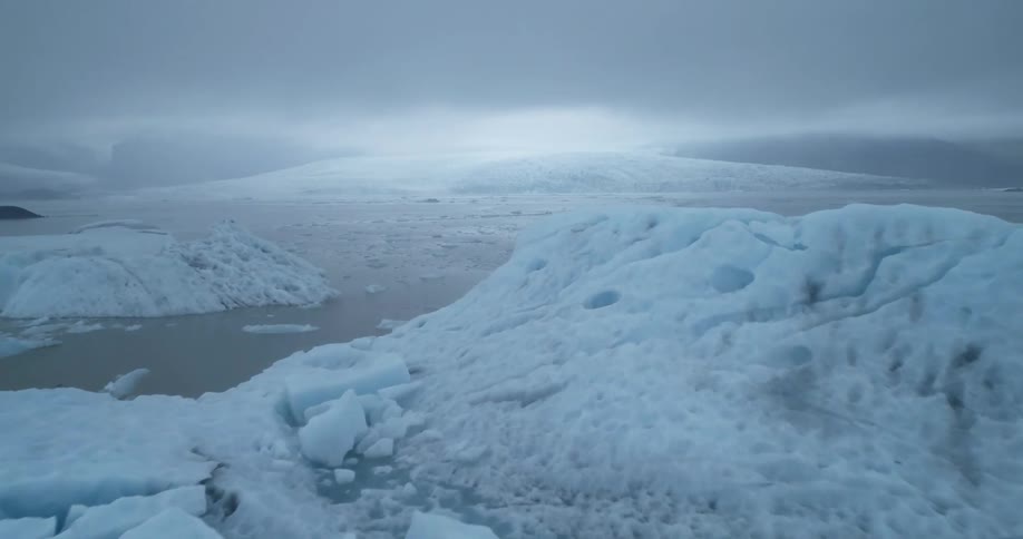 Chunks of ice float in ocean waters near glaciers on a gray day