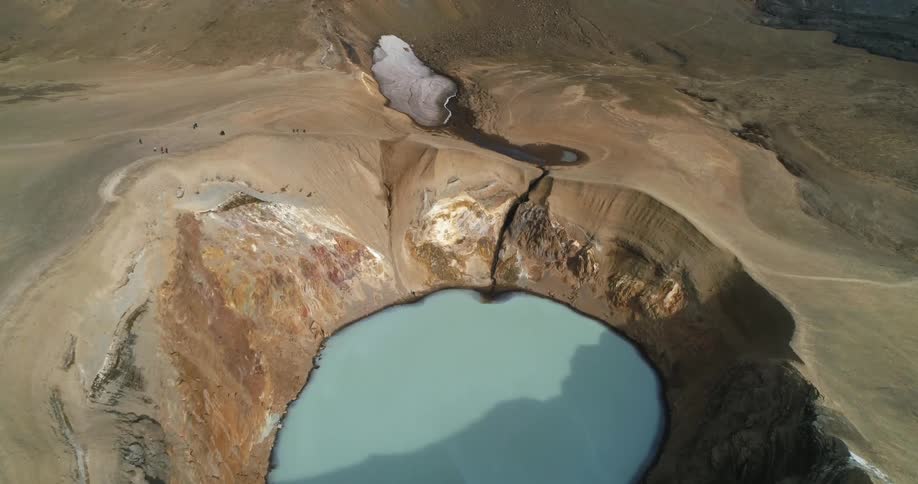 A circular crater with water next to ocean waves splashing on shore