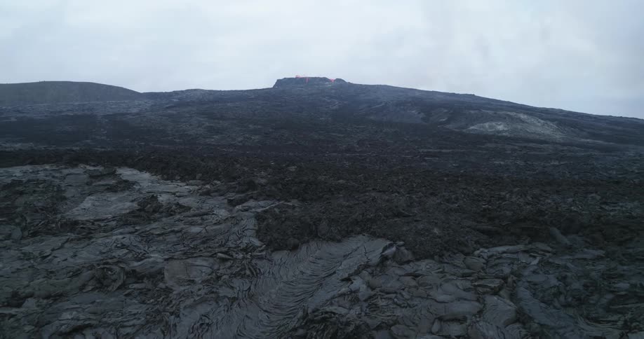 Orange lava glows from the top of a volcano