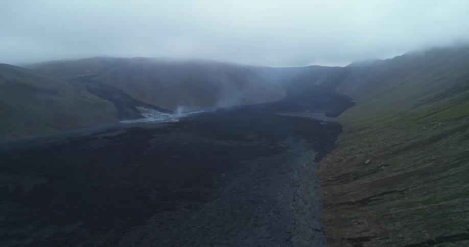 Fog rises over a valley under a hazy sky