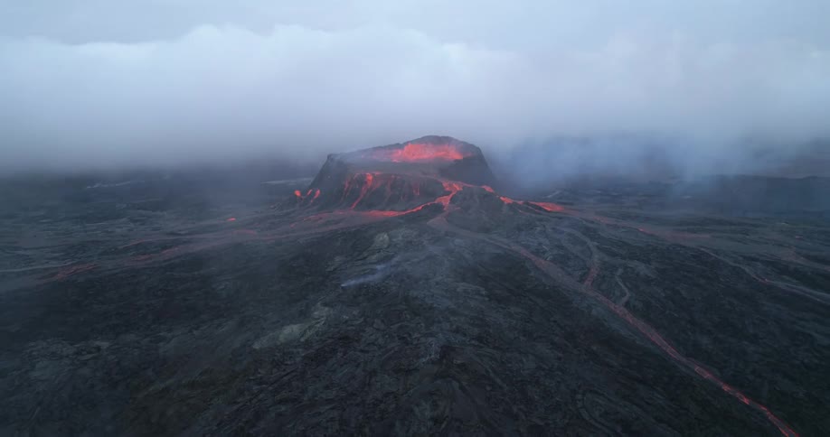 Lava is streaming down the sides of an erupting volcano as smoke fills the air