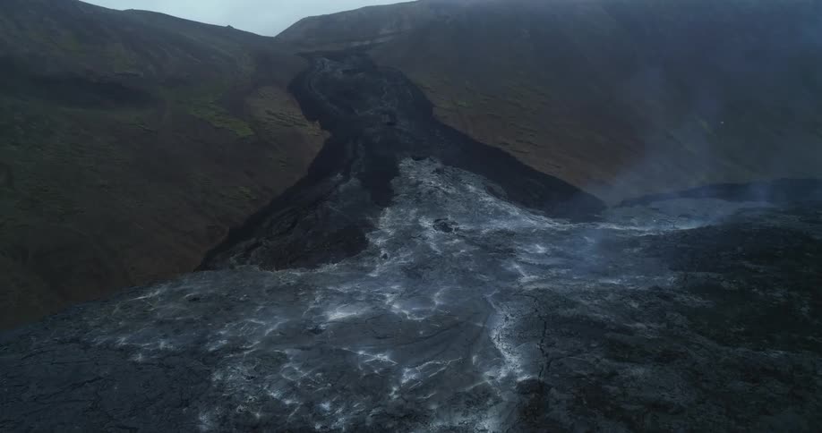 Smoke rises from ash in the valley of a mountain
