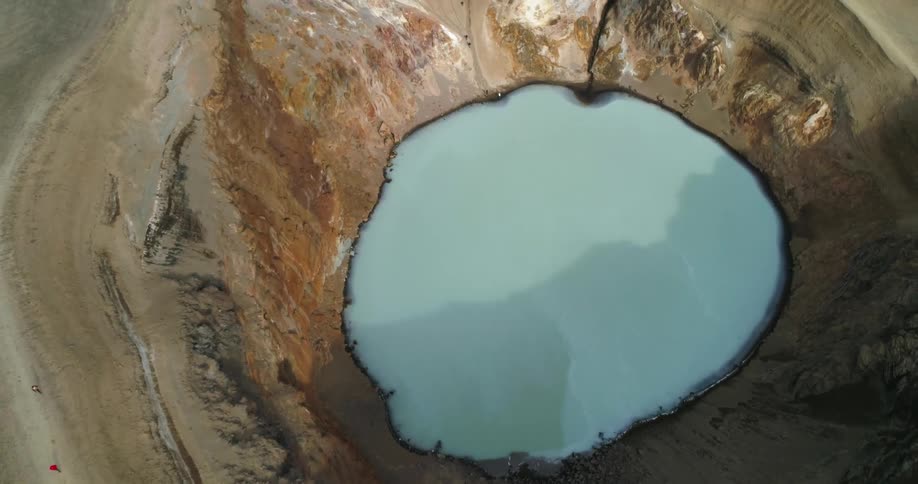 A milky blue hot spring sits at the base of a canyon