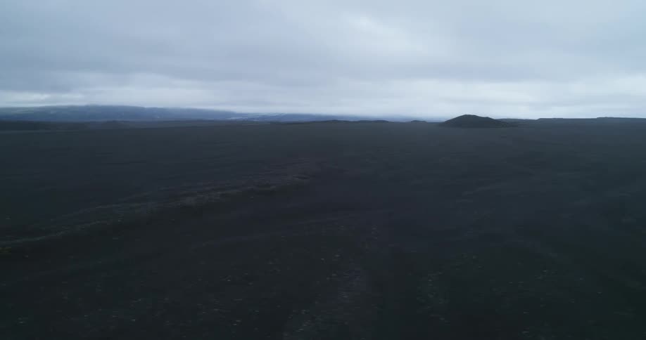 Wide open land and a mound in the distance under a very cloudy sky