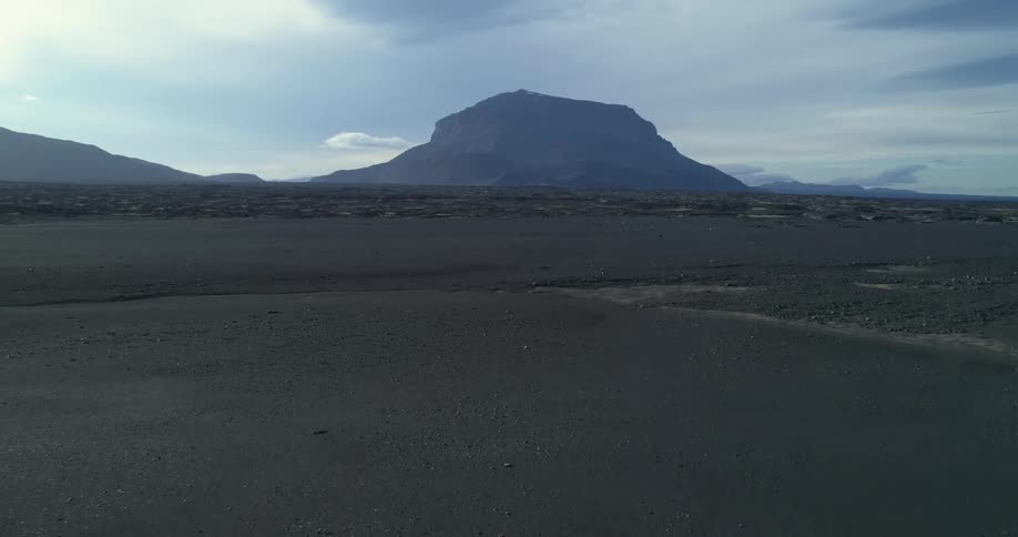 Dirt road winds through desert bordered by hazy mountains sitting on horizon