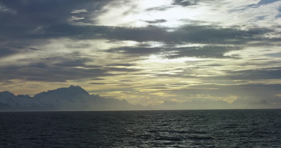 A large ocean has the sun setting in the distance