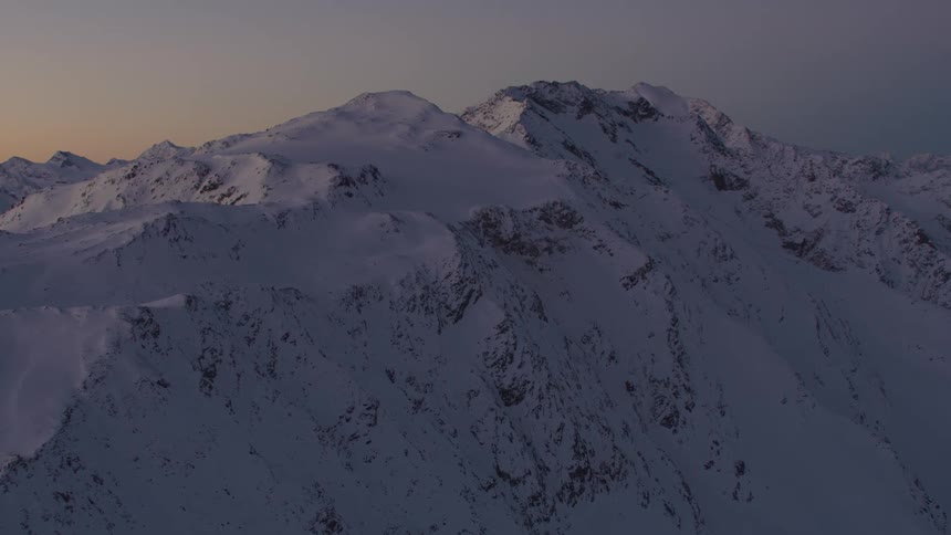The sun rises over snow covered mountains