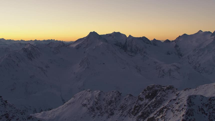 An aerial view of snowcovered mountains in the early morning