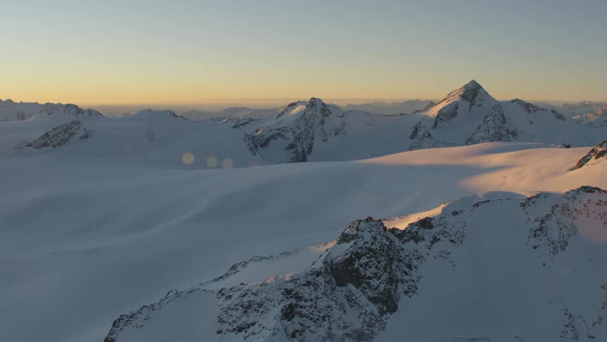 A mountain range covered in snow and ice with the sky and clouds in the background