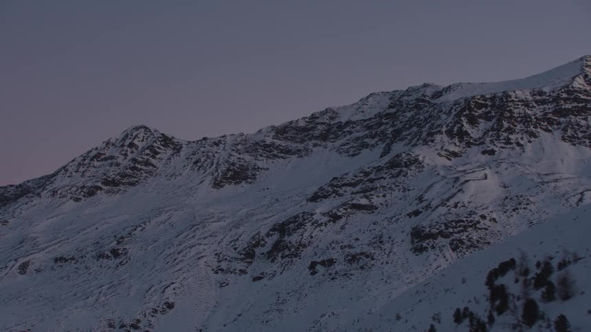 The setting sun turns the sky purple over a mountain range