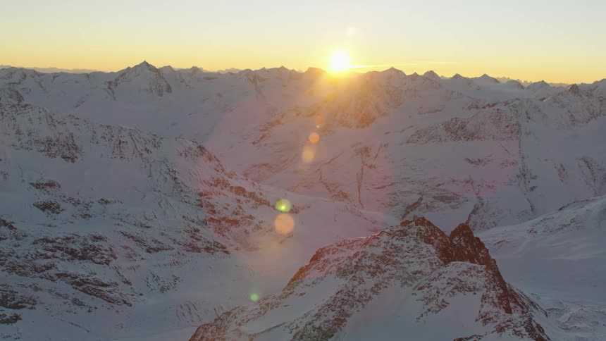 A mountain range covered in snow and ice with the sky and clouds in the background