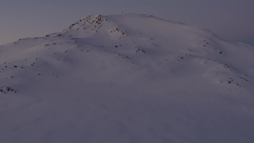 A mountain range covered in snow and ice with the sky and clouds in the background