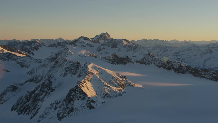 Sunlight shines on the peaks of snow covered mountains