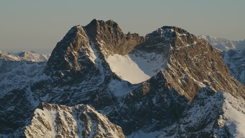 Large mountains are partially covered in snow in the wilderness