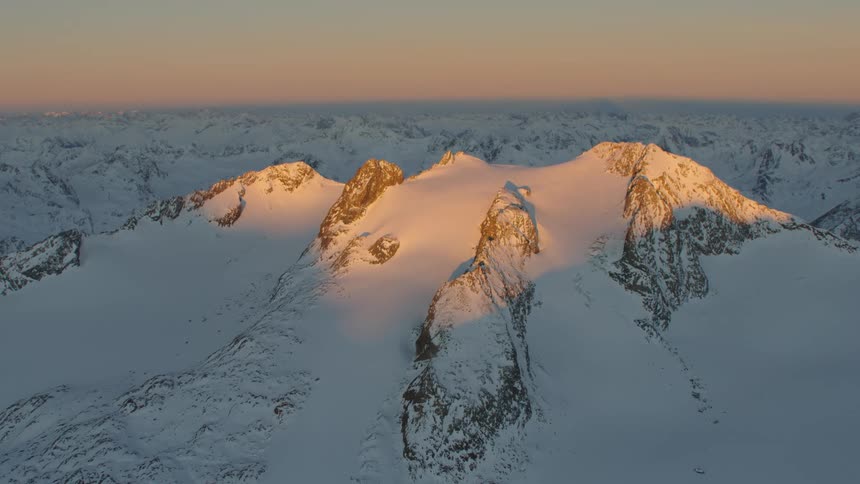 Sunlight shines on summit while remaining mountain range remain under shadow on hazy day