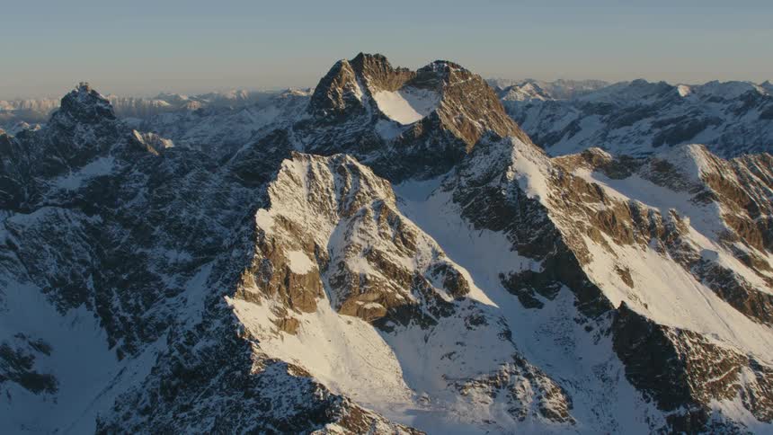 The sun is shining on the snow covered mountain range