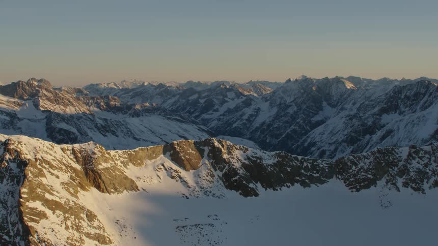 An aerial view of a landscape of snowy rocky mountains in the early morning