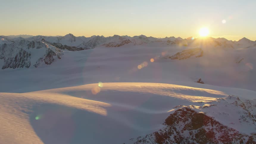 Sun shines over mountains on horizon casting shadow onto valley