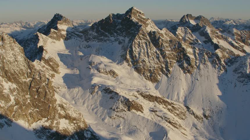 Tall and jagged mountains are partially covered in snow in the wilderness