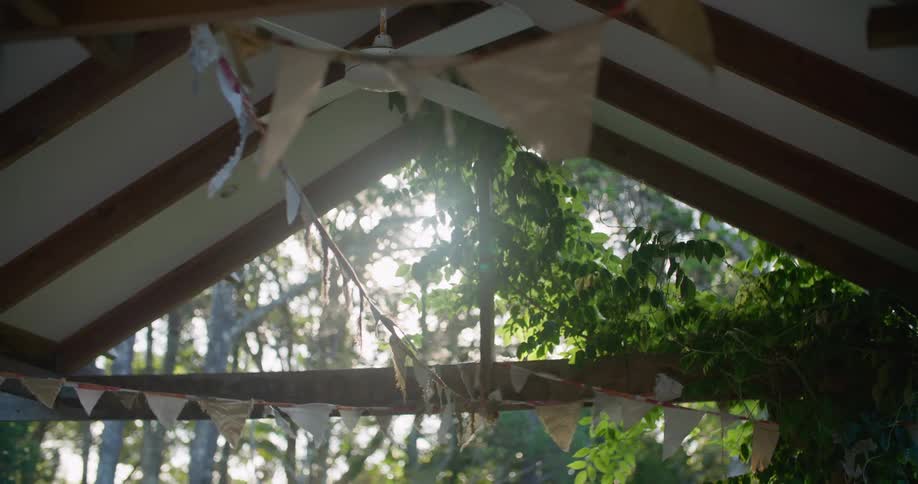 An open air room with a ceiling fan is decorated with streamers on a breezy day