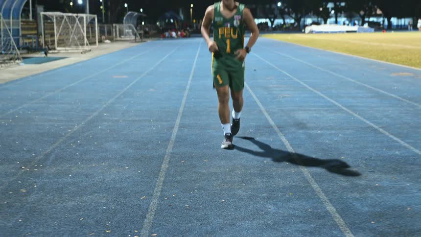 A man running at an outdoor track in a city
