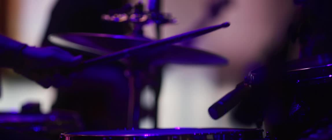 A musician hits drums with drumsticks