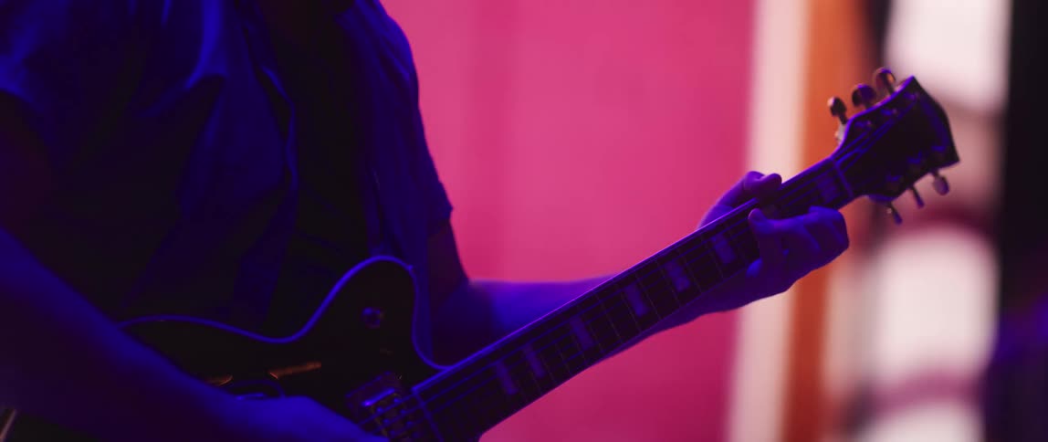 A man is playing the guitar in front of a large display