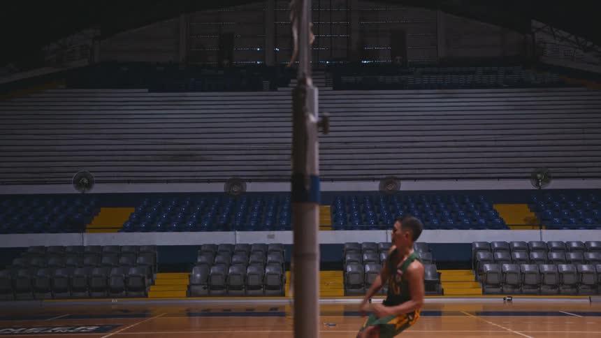 A man spikes the volleyball over the net