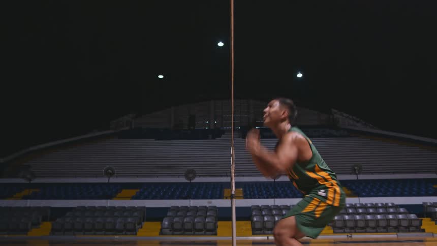A man jumps up to hit a ball over a net inside a stadium