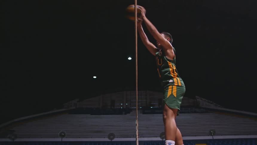 An athlete is practicing volleyball in a sports facility while in full uniform