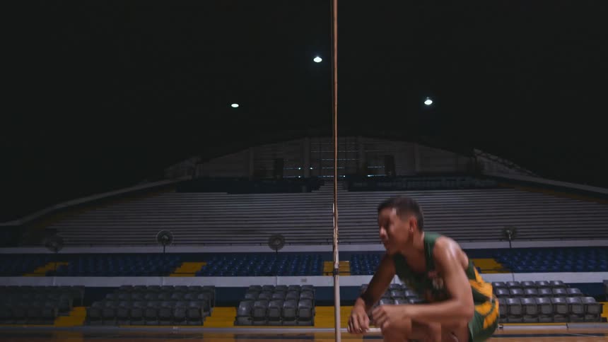 A man is practicing volleyball in full uniform in an empty sports facility