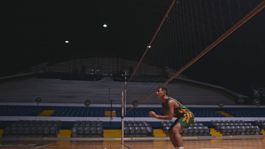 A man in a sports facility is practicing volleyball