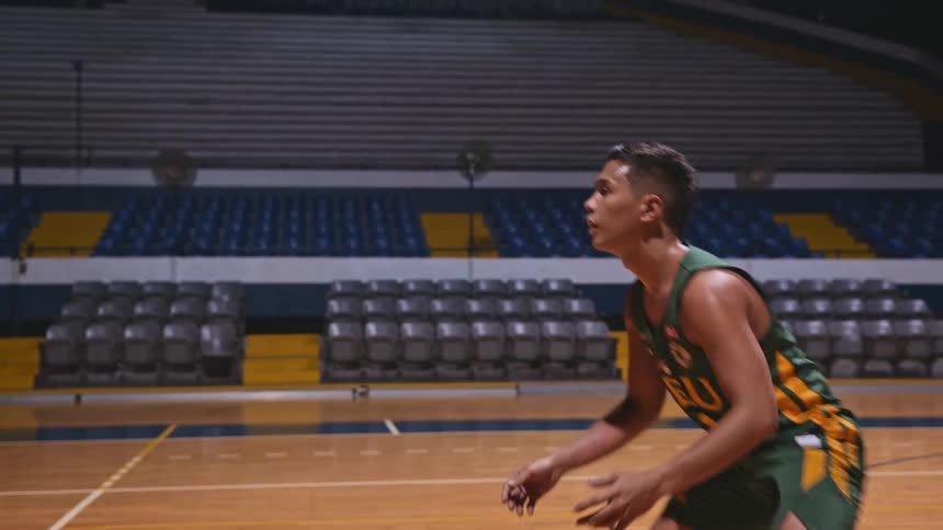 A young man wearing a jersey is hitting a volleyball in a gymnasium