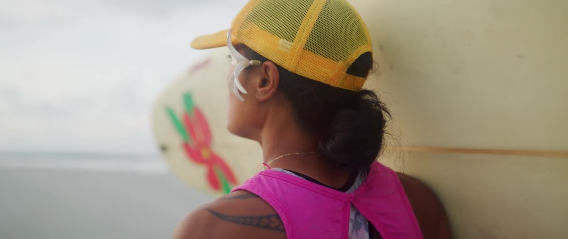 Woman carries surfboard across beach
