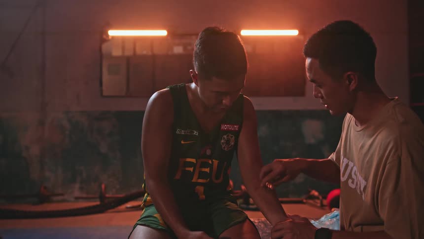 A trainer is rubbing ice on the arms of a young athlete in a gym