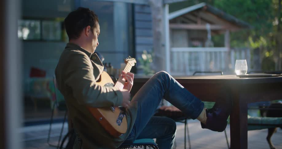 A man plays the guitar on his porch