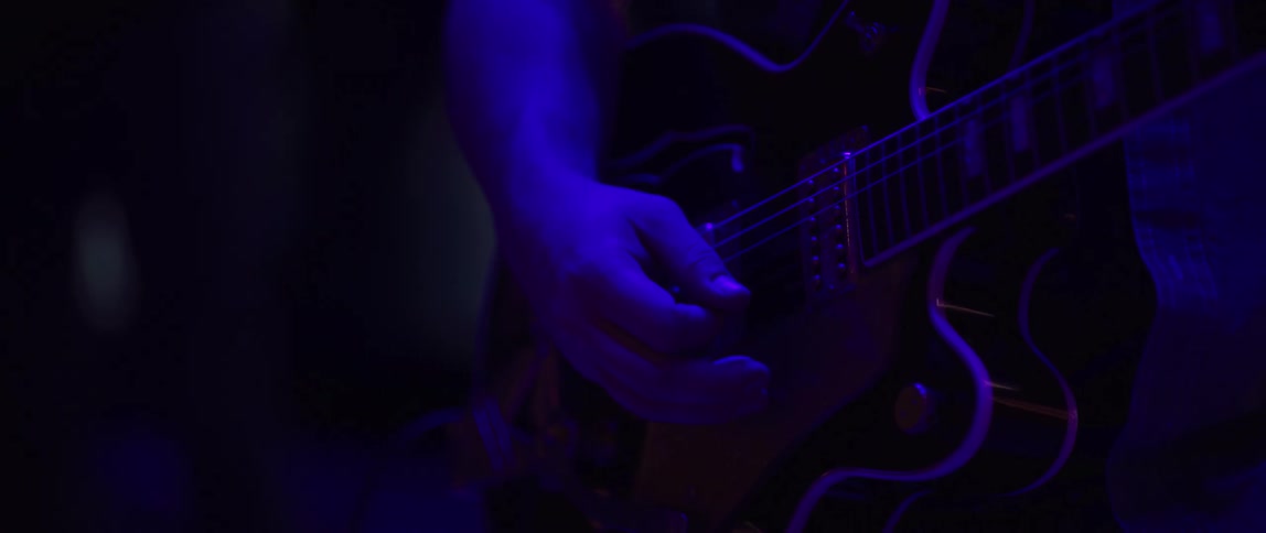 A man is playing the guitar in front of flashing lights at night