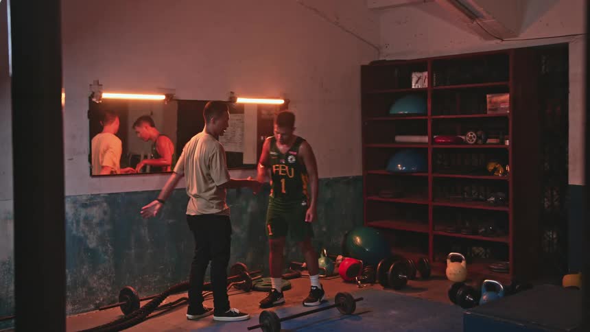 Athlete wearing uniform and friend hug standing in gym near mirroramong weights