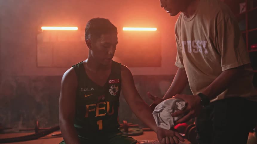 Man examines sitting male athletes armin room lit by neon reddish lights