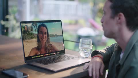 Man and woman talk via video call then wave and kisses