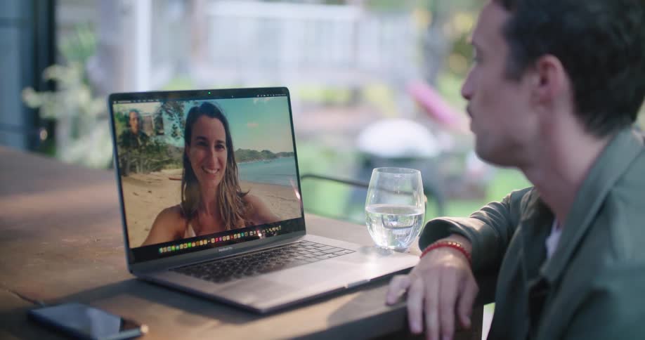 Man and woman talk via video call then wave and kisses