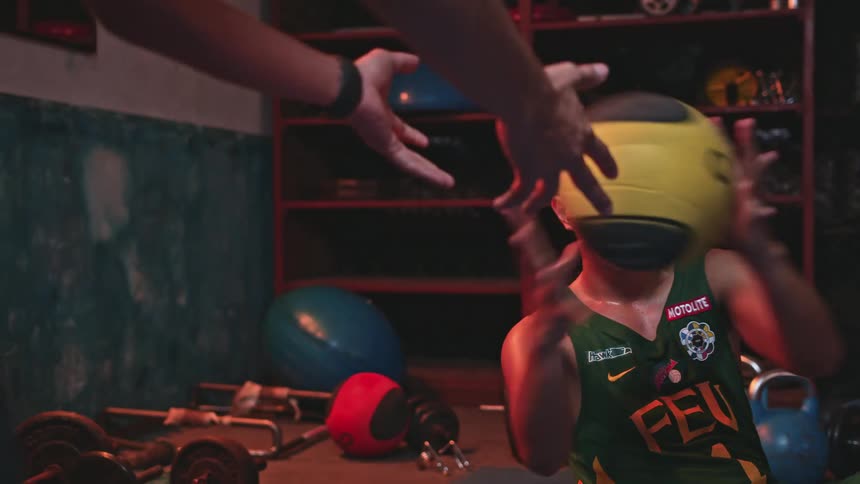 Male athlete sweats while exercising with ball with another mans help