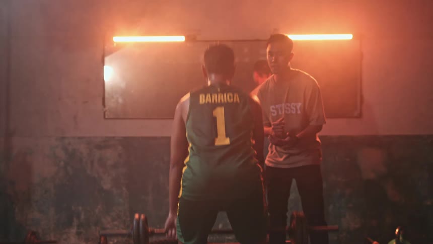 A personal trainer encourages an athlete as he lifts weights in a gym