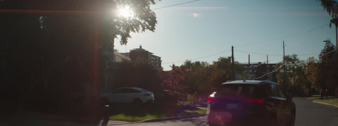 Vehicles drive along a curved street in a suburban neighborhood