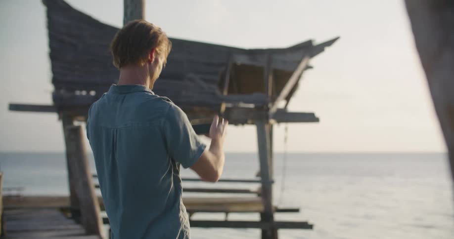 A man taking a photo of the ocean with a smartphone