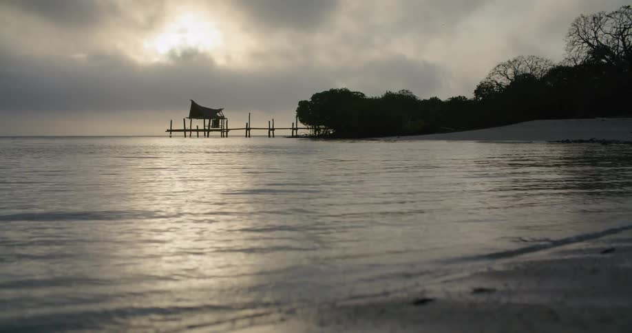 Pier on the coast near a beach at sunset on an overcast day